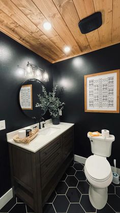 a white toilet sitting next to a sink in a bathroom under a wooden ceiling mounted light