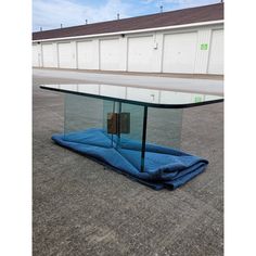 an upside down glass table sitting on the ground in front of a storage area with doors