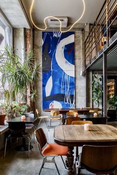 an empty restaurant with tables and chairs in front of a large painting on the wall