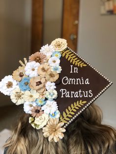 a woman wearing a graduation cap with flowers on it's side and the words in comma paratus written on top