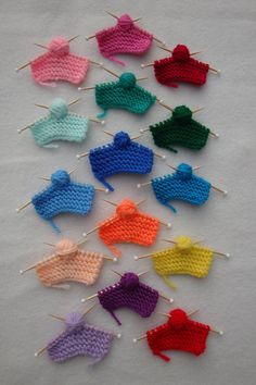 crocheted pins are arranged in rows on a white surface, each with different colors