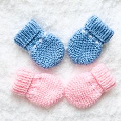 two knitted mittens sitting next to each other on top of a white blanket