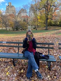 a woman is sitting on a park bench reading a book