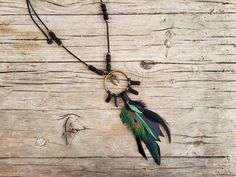 This striking tribal necklace is a true statement piece, featuring a large bronze ring adorned with macrame and beads and cute little bronze angel wing charms.  A black leather feather, paired with a feather charm and a vibrant peacock feather, dangles from the ring for an eye-catching, boho look. The adjustable leather cord strap, partly beaded, allows you to wear it as a choker or a long necklace, making it versatile for any outfit.  Handmade with upcycled materials, this one-of-a-kind necklac Long Boho Necklace, Bronze Green, Long Necklace Boho, Necklace Leather, Feather Necklace, Bronze Ring, Necklace Making, Upcycled Materials, Cluster Necklace