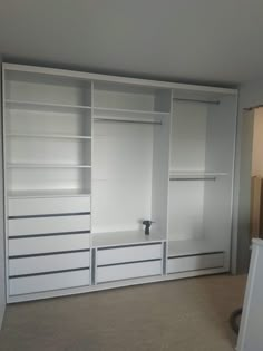 an empty room with white closets and drawers on the wall in front of it