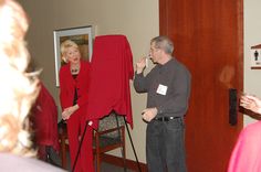 a man and woman standing next to each other in front of a red piece of cloth