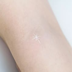 a small white star tattoo on the arm