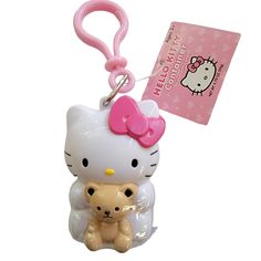 a hello kitty keychain is holding a teddy bear with a pink bow on it