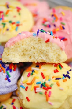 there are many different colored donuts with sprinkles on them and one has a bite taken out of it