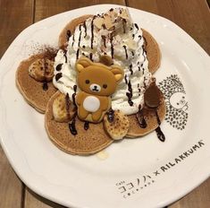 a white plate topped with pancakes covered in whipped cream and a teddy bear on top