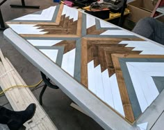 a table made out of wood and painted with white, grey and brown geometric designs