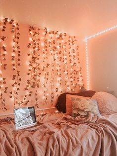 a laptop computer sitting on top of a bed next to a wall covered in lights