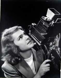 an old black and white photo of a woman looking up at a typewriter on a tripod