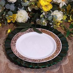 a white and green plate sitting on top of a wooden table next to yellow flowers