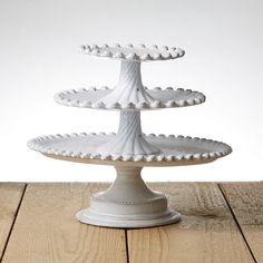 three tiered white cake stand on top of a wooden table