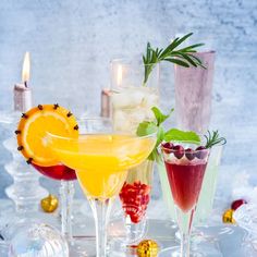 three different types of cocktails on a white tray with candles and decorations around them