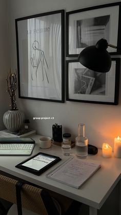 a white desk topped with two framed pictures next to candles and a tablet computer on top of it