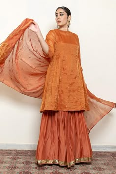 Rust kurta with embroidered floral and half moon motifs. Comes with an inner, matching gharara and chanderi silk dupatta.
Components: 4
Pattern: Embroidered
Type Of Work: Thread, Sequin
Neckline: Round
Sleeve Type: Three quarter
Fabric: Kurta: Chanderi Tissue, Gharara: Cotton Silk, Dupatta: Chanderi Silk, Lining: Cotton
Color: Orange
Other Details: 
Straight silhouette
Kurta side gathers
Occasion: Sangeet,Mehendi and Haldi - Aza Fashions Tissue Fabric Dress Design, Chanderi Kurta Designs, Orange Indian Outfit, Plazo Outfits, A Line Kurti Designs, Sharara Design, Girls Lehenga, Kurta With Sharara, Haldi Decor