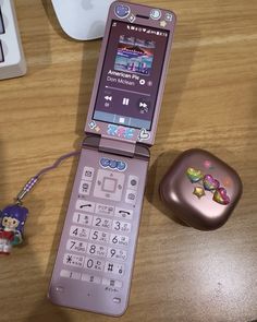 a pink cell phone sitting on top of a wooden table next to a computer mouse