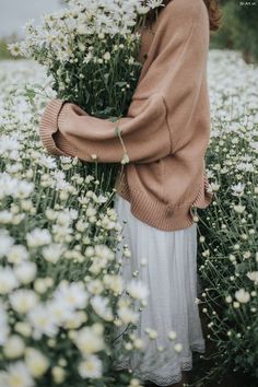 a woman standing in a field of white flowers