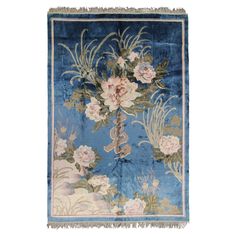 a blue rug with flowers on it and fringes hanging from the top of it