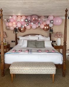 a bed with pink and silver balloons hanging above it