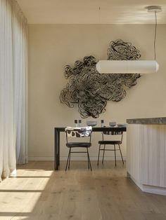 a dining room table and chairs in front of a wall sculpture