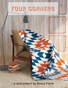 an orange and blue blanket sitting on top of a wooden chair next to a lamp