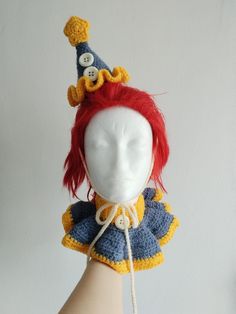 a crocheted doll wearing a hat with buttons on it's head and red hair