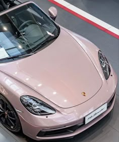 a pink sports car is on display in a showroom with its hood up and the top down