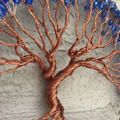 a wire tree sculpture with blue glass beads on it's branches and the roots