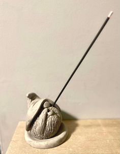 a small sculpture with a long black stick sticking out of it's mouth