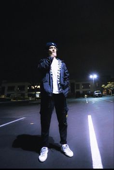 a man standing in the middle of a parking lot at night