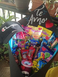 a box filled with candy and candies sitting on top of a wooden table next to a potted plant