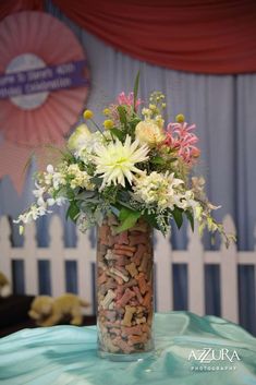 a vase filled with lots of flowers sitting on top of a blue tablecloth covered table