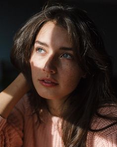 a woman with freckled hair and blue eyes is looking at the camera while sitting down