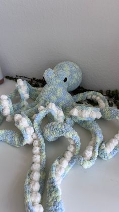 an octopus stuffed animal sitting on top of a white table next to some yarn balls