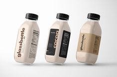 three milk bottles with labels on them sitting side by side in front of a white background