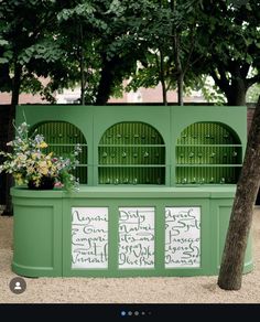 a green bench with writing on the side and trees in the backgrounge