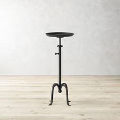 a round table with an iron stand on the top and two hooks in the middle