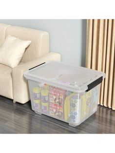 a living room with a white couch and plastic storage containers on the floor next to it