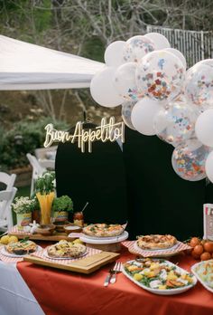 a table topped with lots of food and balloons