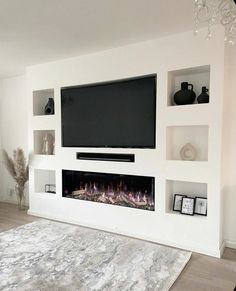 a living room with white walls and a large flat screen tv mounted on the wall