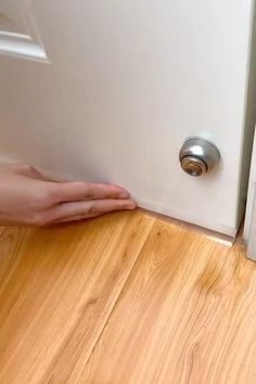 a person's hand is on the floor next to a door with a handle