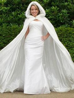 a woman in a white wedding gown and cape