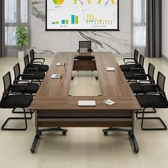 a large conference table with chairs around it in front of a projector screen on the wall