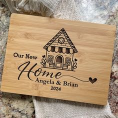 a personalized cutting board with the words, our new home and an image of a house on it