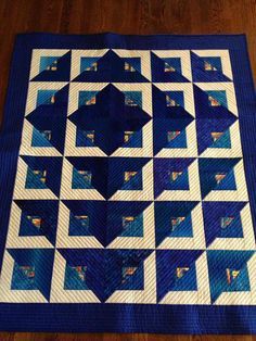 a blue and white quilted table topper on a wooden floor with an image of a star in the center