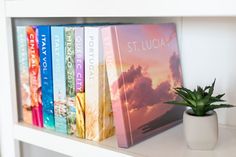 a white shelf with books and a potted plant