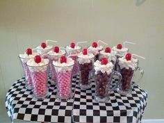 there are many cups with candy in them on the checkerboard tablecloths